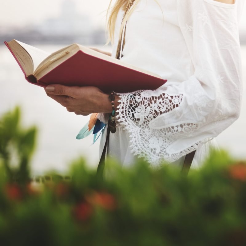 Woman reading a book by the water